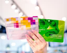 November Staff Picks | 8th Street Canna Close-up of a hand holding cannabis edible packages under bright store lighting, representing 8th Street Canna’s November staff picks and favorite cannabis products of the month.